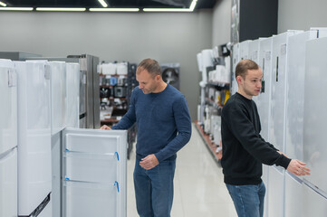 Two Caucasian men are choosing a refrigerator in a hardware store.