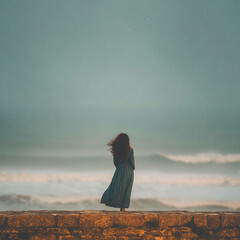 photo of young woman on the sea or ocean shore, standing with her back, untied dark hair develop in the wind, long dress, seascape, can be used as a poster or banner