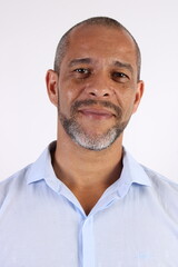 Obraz premium Portrait of a smiling mature Brazilian man wearing a light blue shirt, clean white background, professional headshot.