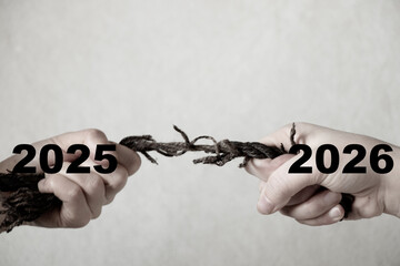 Two female hands pull a rope in opposite directions with the numbers 2025 and 2026, symbolizing the change of year, confrontation, choice, and transition between the past and future