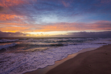 Obraz premium Colorful Sunrise Over Ocean Waves and Sandy Beach