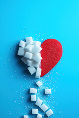 Red heart and sugar cubes symbolizing diabetes awareness on blue background with copy space for World Diabetes Day November 14