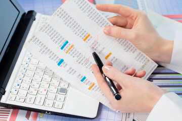 A woman works with business papers, on a report. Close-up of her hands.