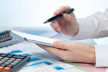 A woman working with a tablet on an accounting report. Close-up of her hands.