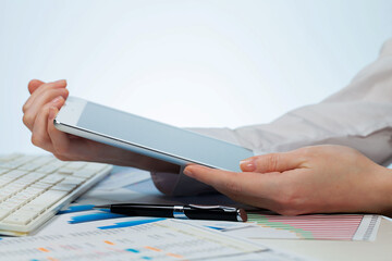 A woman working with a tablet on an accounting report. Close-up of her hands.
