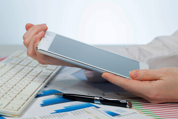 A woman working with a tablet on an accounting report. Close-up of her hands.