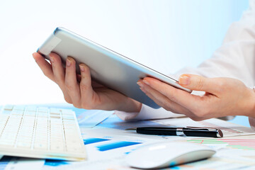 A woman working with a tablet on an accounting report. Close-up of her hands.
