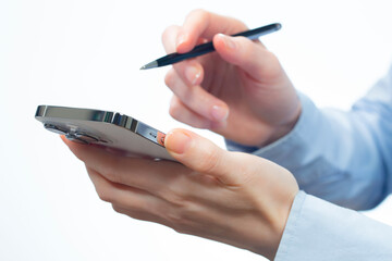 A woman works with a smartphone in the office, on a report. Close-up of her hands. 	