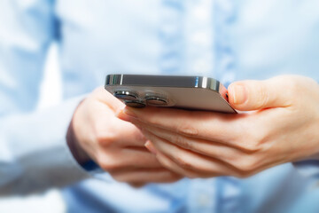 A woman works with a smartphone in the office, on a report. Close-up of her hands. 	