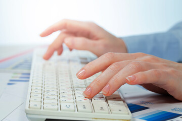 A woman working on an accounting report with a computer. Close-up of her hands.