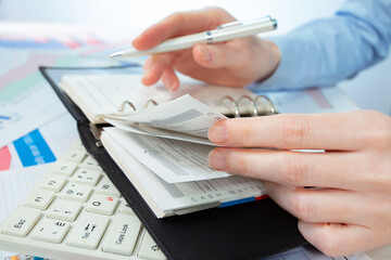A woman works with business papers, on a report. Close-up of her hands.