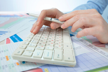A woman working on an accounting report with a computer. Close-up of her hands.