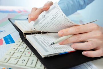 A woman works with business papers, on a report. Close-up of her hands.