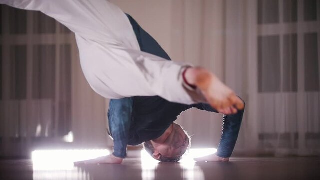 Martial arts. A professional man performing an acrobatic capoeira elements leaning on his hands