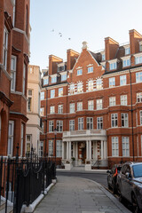 Obraz premium Stroll along Hans Crescent with elegant red brick townhouses and vibrant city life Knightsbrigde in London