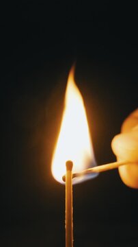 One match is lit by another, burning down until it extinguishes against a dark background. The isolated flame glows brightly in extreme close-up and slow motion, creating a dramatic and mesmerizing