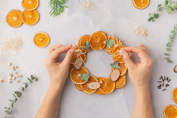 A decorative wreath crafted from dried orange slices, eucalyptus leaves, dried cloves, wooden cuts step by step instruction diy