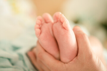 Close-up of delicate newborn feet held by a parents hand, illustrating the pure love, care, and tenderness that surround a newborn from the very first days of life.