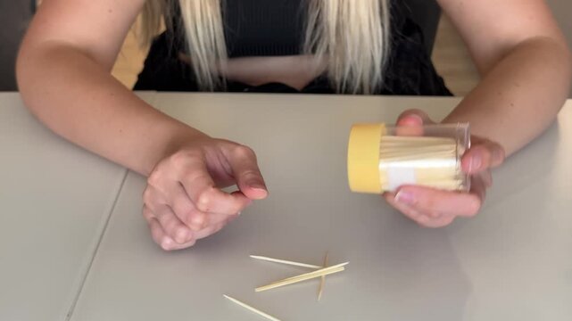 Caucasian woman pouring toothpicks from jar onto table