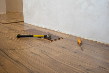 Tools rest on freshly laid wooden floor as home renovation takes place in a well-lit living space, showcasing the progress of the project