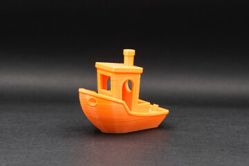 Orange 3D printed miniature boat on black background