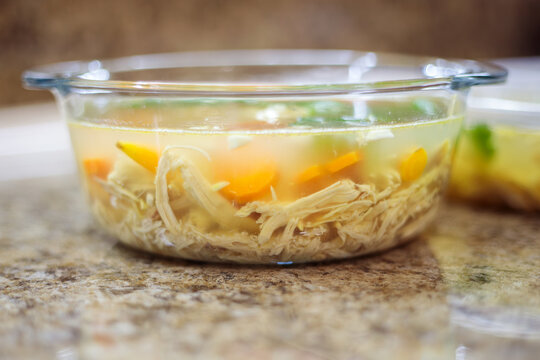 Several plastic containers with homemade meat jelly or holodets standing in a row on a kitchen counter during the cooling and setting process