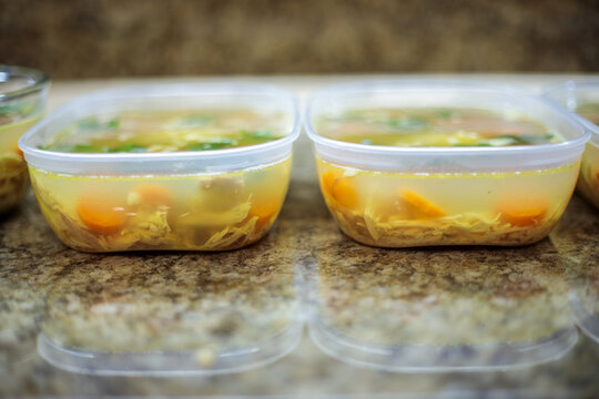Several plastic containers with homemade meat jelly or holodets standing in a row on a kitchen counter during the cooling and setting process