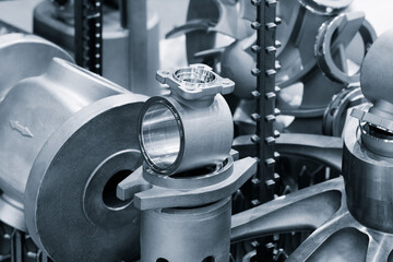 Fototapeta premium A collection of metal parts manufactured on a modern programmable metalworking CNC machine lie on the machine's metal work table, industrial metalworking concept background.