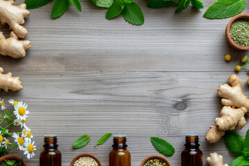 Flat lay composition of natural herbal ingredients on a light gray wooden background, ginger roots, fresh mint leaves, chamomile flowers, dried herbs in small bowls, and amber glass essential oil.