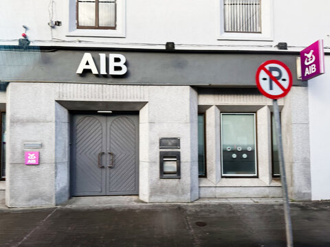 AIB bank building in Ireland with gray doors, modern storefront, and no parking sign