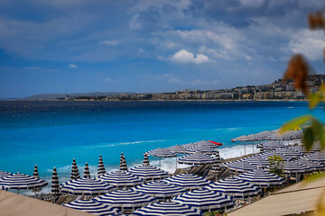 Striped umbrellas line a beach with turquoise Mediterranean waters, Nice, France