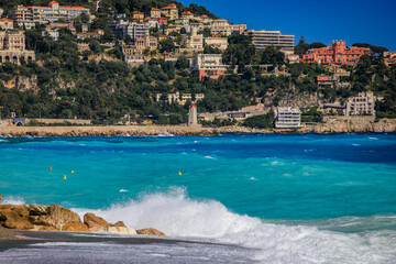 Striped umbrellas line a beach with turquoise Mediterranean waters, Nice, France