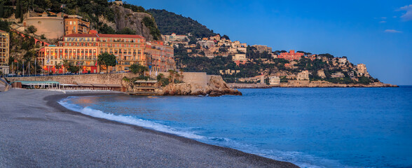 Elegant buildings above the beach and Mediterranean sea at sunset, Nice, France