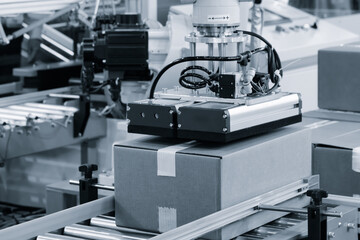 robotic arm places cardboard box on conveyor belt  distribution warehouse for storage or delivery of an online order mail shipment. Modern technologies, logistics, storage delivery concept background.