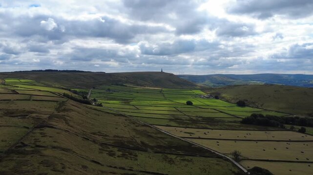Aerial view of the landscape at Erringdon Grange near Hebden Bridge showing meadows with cows and sheep grazing and Stoodley Pike Moor and monument in the distance