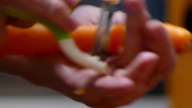 Close-up of hands peeling a fresh, vibrant orange carrot with a metal peeler on a clean white background. Concept of healthy eating, cooking, and food preparation.