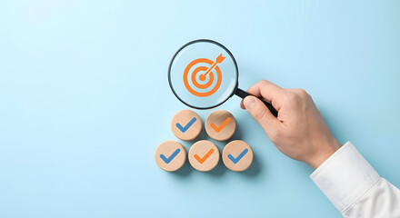 hand holding magnifying glass over target and checkmarks on wooden blocks