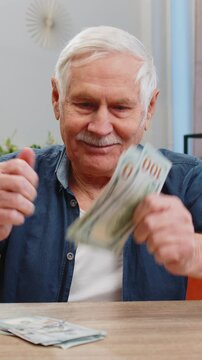 Planning family budget. Happy senior man counting money cash calculate domestic bills at home. Elderly old grandfather satisfied of income salary pension and saves money for planned vacation gifts