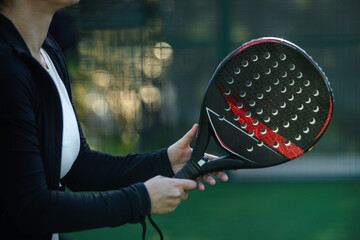 Close up photo of woman with Padel tennis racket on the court. Girl athlete with paddle racket on...