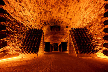 Naklejka premium Riddling or remuage sediment to the bottle neckin deep underground caves on pupitre wooden racks, traditional method making champagne sparkling wine in Reims, Champagne, France