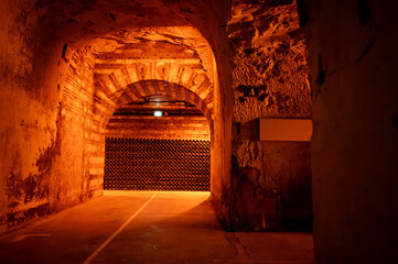 Visit of deep and long underground caves with dusty bottles on racks, traditional method making champagne sparkling wine in Reims, Champagne, France