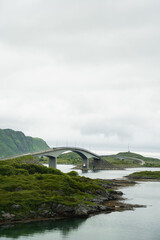 Obraz premium bridge curving over the sea with green hills, Lofoten, Norway
