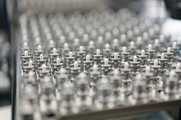 Metal parts are arranged in neat rows on a work table in a factory during a busy workday in the...