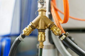 Pipes connect to a brass splitter in a workshop setting during daytime work hours