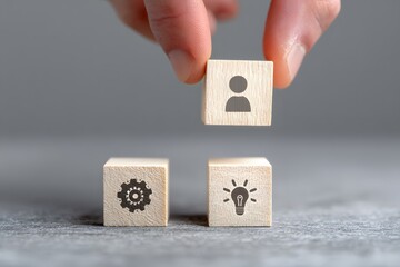 A person's hand placing wooden blocks with a head symbol, representing the process of knowledge transfer and skill exchange