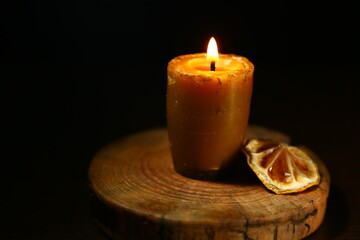 Burning wax one candle in a candlestick isolated on dark black background. Closeup
