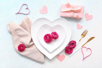 Table setting for Valentine's Day with rose flowers, gift box and paper hearts on blue grunge...