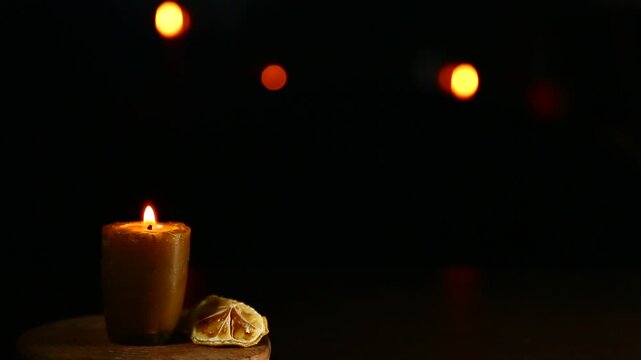 Bees wax candle burning light on wooden candlestick for mood, relaxation, meditation dark black background with many bright lights. Atmosphere mood decoration with homemade single candle flame