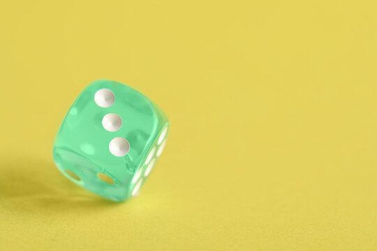 Turquoise game dice on yellow background