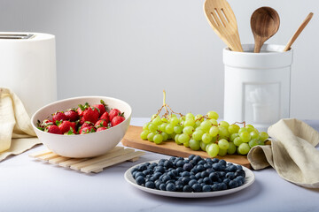 Containers with strawberries, blueberries, and green grapes.